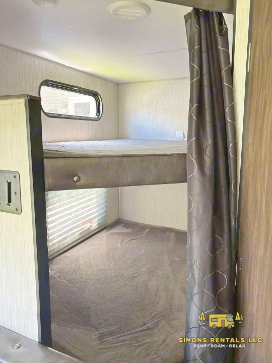 Cozy bunk beds in this RV rental, offering two sleeping levels, windows for natural light, and a privacy curtain.. Forest River Cherokee Grey Wolf Special Edition 2020