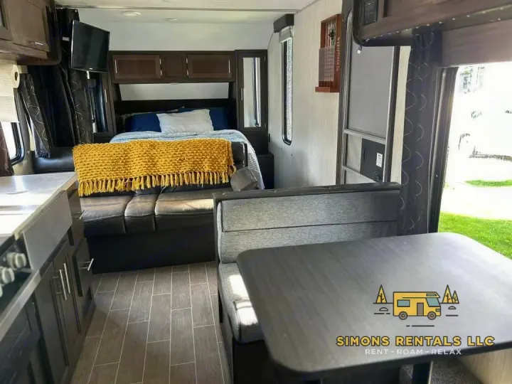 Step into this spacious RV rental interior, featuring a comfortable bedroom, kitchen, and dinette area. Perfect for your next adventure!. Forest River Cherokee Grey Wolf Special Edition 2020