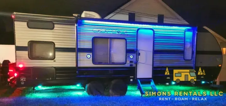 This illuminated rv rental travel trailer shines brightly at night with blue awning lights and green underglow, ready for adventure.. Forest River Cherokee Grey Wolf Special Edition 2020