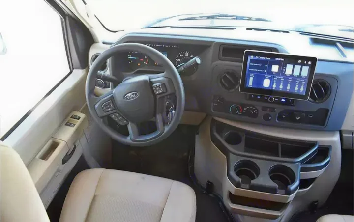 RV rental driver's cabin featuring a Ford steering wheel, dashboard with digital RV control panel, and cup holders.. Thor Eddie Bauer 2025
