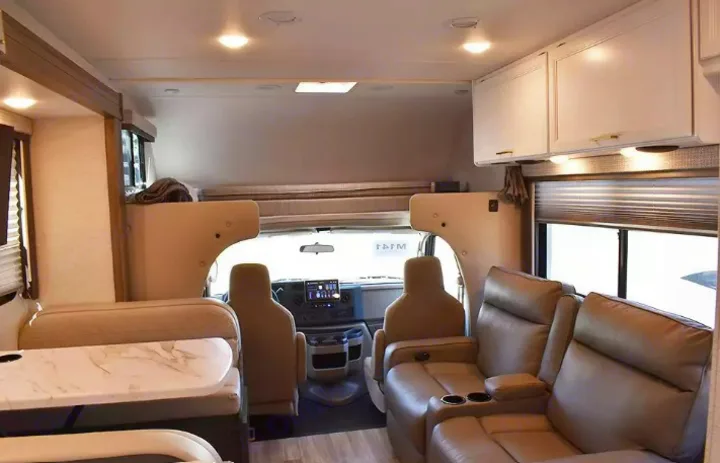 Inside an RV rental, featuring a front cabin, an over-cab bunk bed, a dinette, and two plush recliners with cupholders.. Thor Eddie Bauer 2025