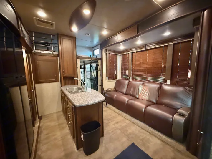 Spacious RV rental interior featuring a modern kitchenette, comfortable brown leather sofa, and bunk beds. Perfect for family adventures.. Keystone Fuzion 2016