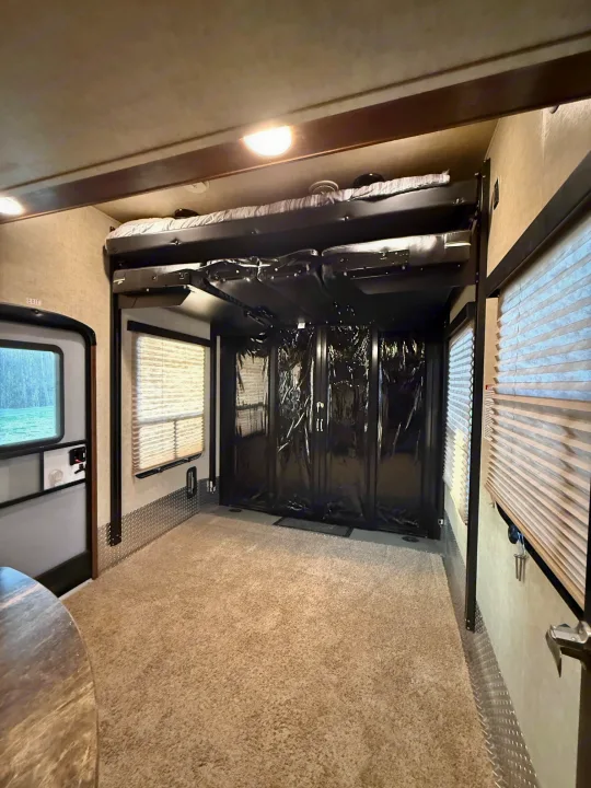 RV rental interior: a versatile toy hauler garage with elevated bunk beds, protective black screens, large windows, and soft carpet.. Keystone Fuzion 2016
