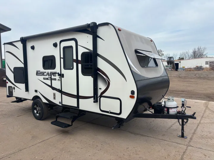 A white and grey travel trailer, an ideal RV rental, parked on concrete with its awning retracted.. KZ Escape 2018