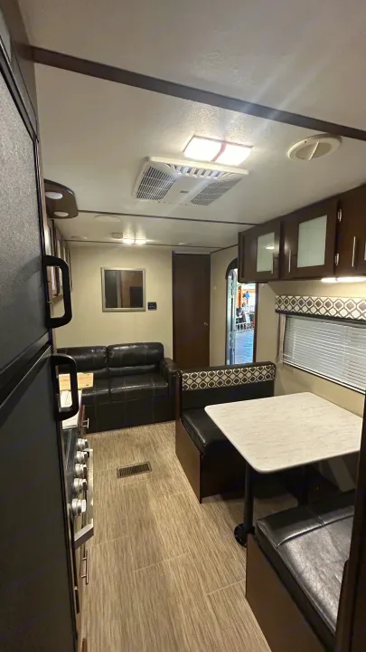 Explore this modern RV rental interior featuring a compact kitchen, comfortable dining booth, and cozy living space.. Primetime Avenger 2019