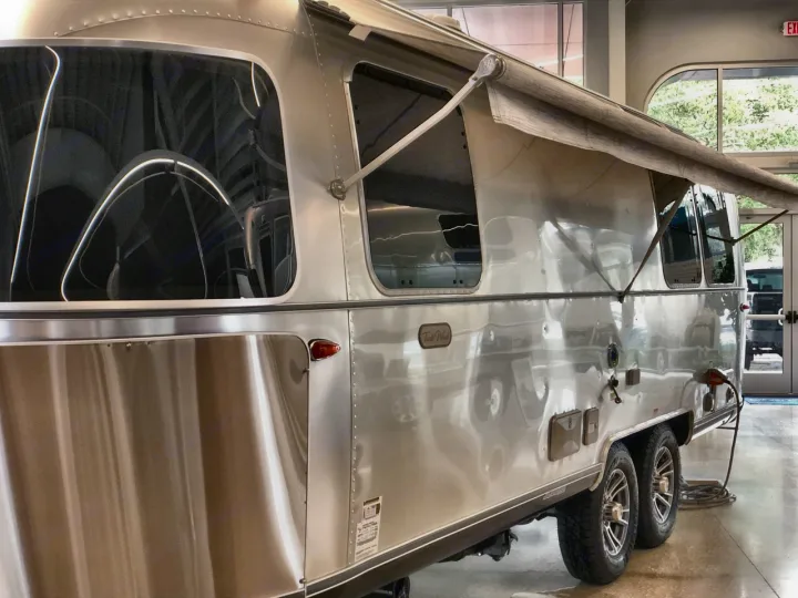 Sleek Airstream travel trailer with awning extended, showcasing its iconic silver design. Perfect for your next rv rental adventure.. Airstream Trade Wind 2025