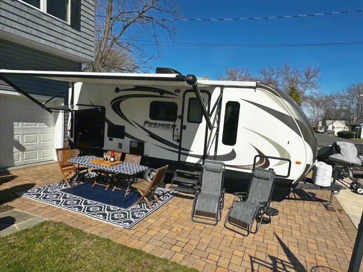 Enjoying the comforts of an RV rental with a cozy outdoor patio setup, including a table, chairs, and awning.. Keystone RV Bullet Premier 2015