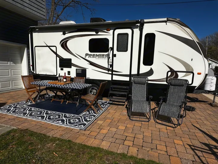 Premier RV rental with a cozy outdoor dining and lounge setup on a paver patio, perfect for relaxation.. Keystone RV Bullet Premier 2015