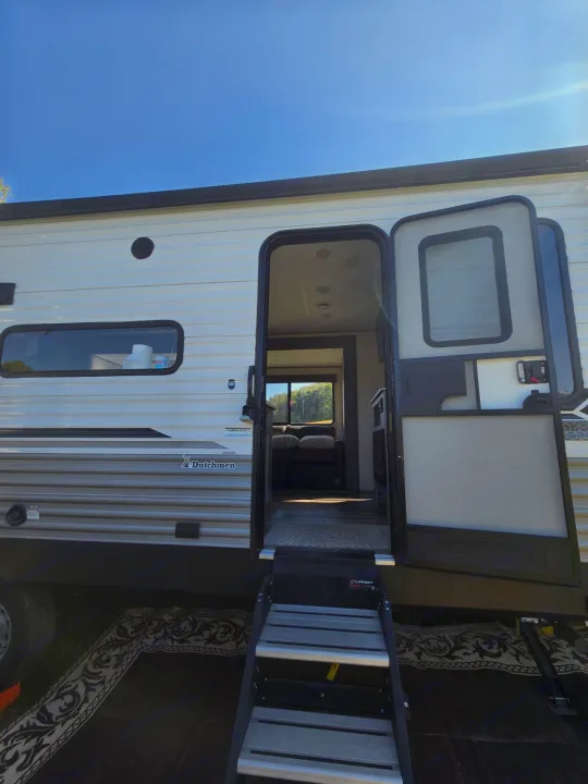 Experience an rv rental! This Dutchmen travel trailer features an open door with steps, offering a glimpse of the comfy interior.. Coleman Lantern LT 26BH 2022