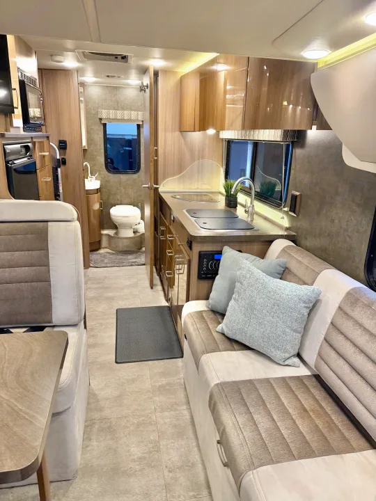 Modern RV rental interior with kitchen, living area, and bathroom access, showcasing compact, well-designed spaces.. Winnebago Trend 2015