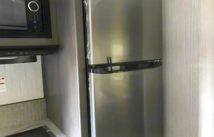 Modern RV rental kitchen with stainless steel microwave, range hood, and refrigerator (protective film visible).. Cruiser RV MPG Ultra Lite 2021