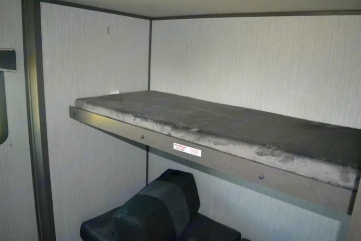 RV rental bunk bed with grey cushion and 275 lbs weight limit sticker, providing a compact sleeping area.. Cruiser RV Shadow Cruiser 2020
