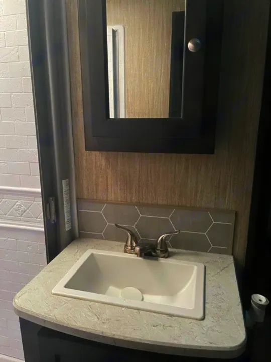Compact RV rental bathroom vanity featuring a white sink, silver faucet, mirrored medicine cabinet, and hexagonal backsplash.. Cruiser RV Shadow Cruiser 2020