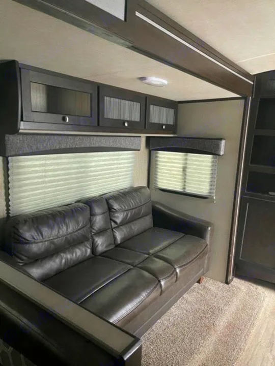 RV rental living space: dark sofa, overhead cabinets, and windows with blinds. A modern and comfortable interior.. Cruiser RV Shadow Cruiser 2020