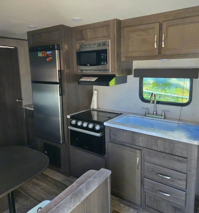 This RV rental features a well-equipped kitchen and dining area, including a fridge, microwave, stove, and sink.. Jayco Jay Flight SLX 2021