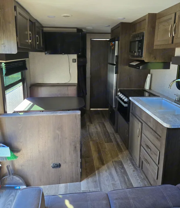 RV rental's modern interior: well-equipped kitchen, dining booth, and living area with wood-look flooring.. Jayco Jay Flight SLX 2021