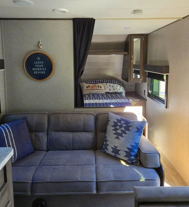 Cozy RV rental interior with a gray sofa, bunk bed, window, and inspirational decor. Perfect for travel adventures.. Jayco Jay Flight SLX 2021