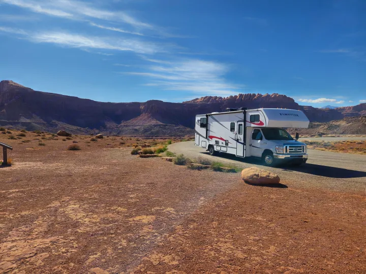 White Class C RV rental parked on a desert road, surrounded by stunning red rock formations under a blue sky.. Forester LE 2023