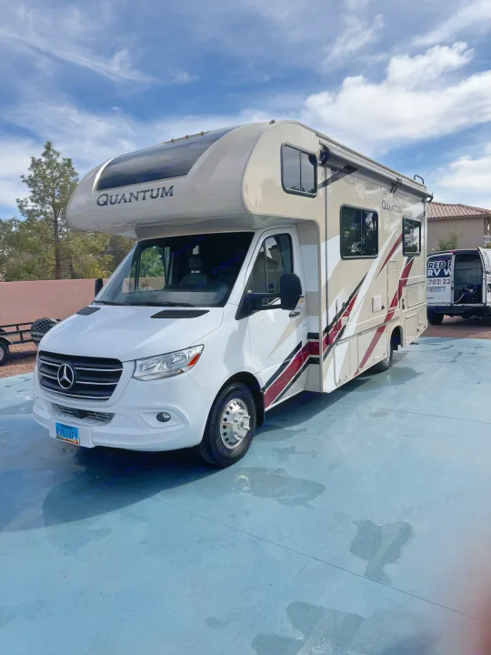This sleek white Mercedes-Benz Quantum RV, gleaming under a sunny sky, is perfect for your next rv rental adventure.. Thor Quantum 2021
