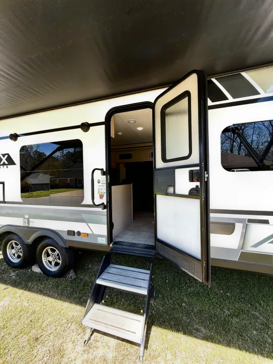 This RV rental showcases an open door with steps and an extended awning, inviting outdoor adventures.. Coachmen Apex 2022