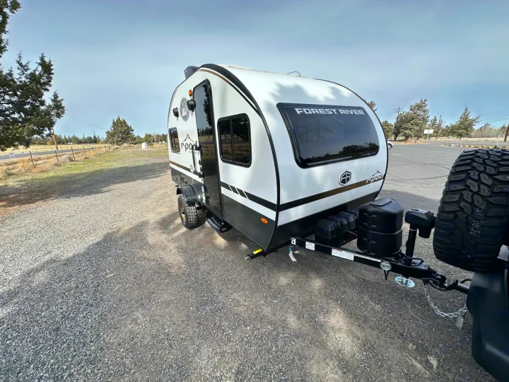 A white and black Forest River R-Pod travel trailer, perfect for your next rv rental adventure, parked on a gravel lot.. Forest River RPod 2026