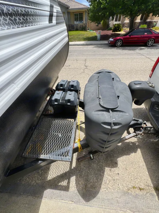 RV rental travel trailer's front hitch area, showing propane tank cover, two battery boxes on a cargo rack.. Coleman Cch 2022