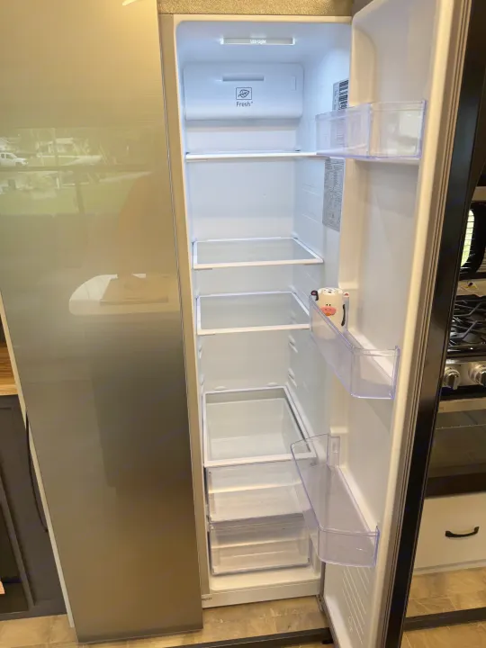 Empty, clean refrigerator in an RV rental, showing shelves, Fresh+ crisper, and door storage. Ready for your adventure!. Forest River Coachman Chaparral 2025