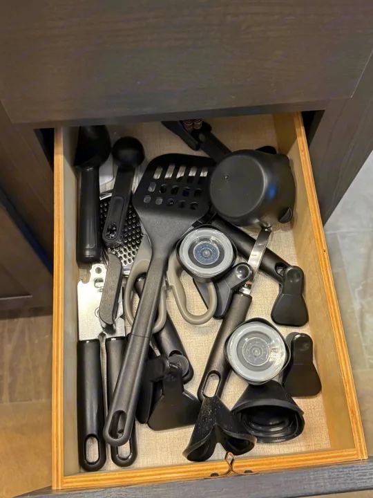 RV rental kitchen drawer: black and gray cooking utensils like spatulas, grater, scoops, and clips, neatly packed for travel.. Forest River Coachman Chaparral 2025