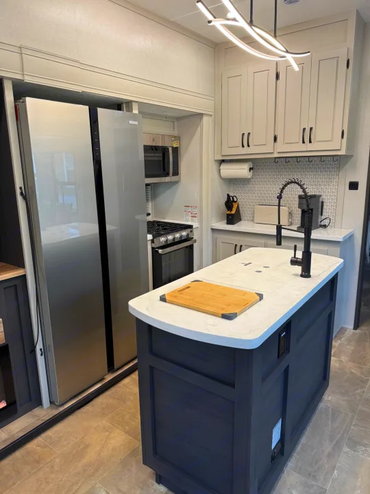 Sleek rv rental kitchen: bright modern design with stainless steel fridge, gas stove, and kitchen island with sink/faucet.. Forest River Coachman Chaparral 2025