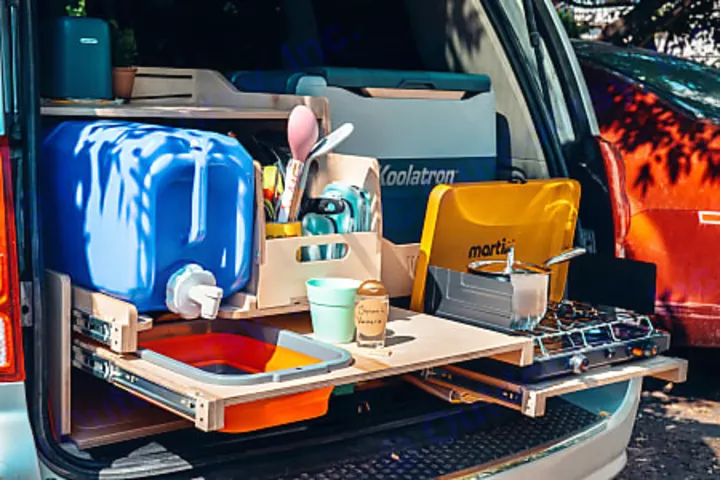 An organized RV rental campervan kitchen with a pull-out water dispenser, camping stove, and cooler for convenient outdoor meals.. Dodge 2022
