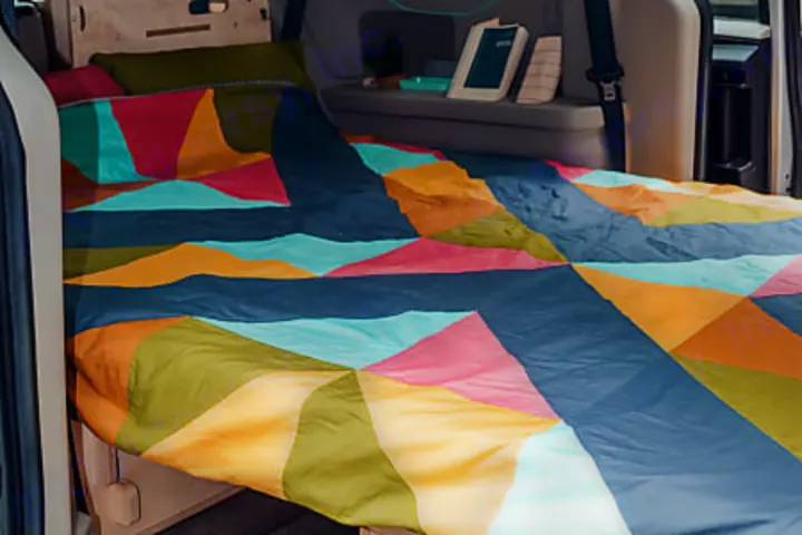 Cozy, colorful bed setup in an RV rental, featuring a vibrant geometric blanket. Ideal for comfortable road trip adventures.. Dodge 2022