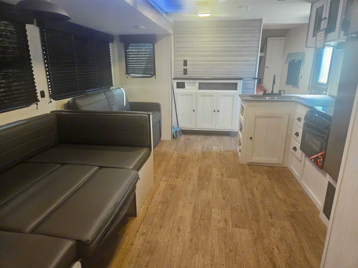 Spacious RV rental interior with L-shaped seating, modern kitchen, and wood-look flooring, ideal for travel.. Heartland RVs Trail Runner 2024