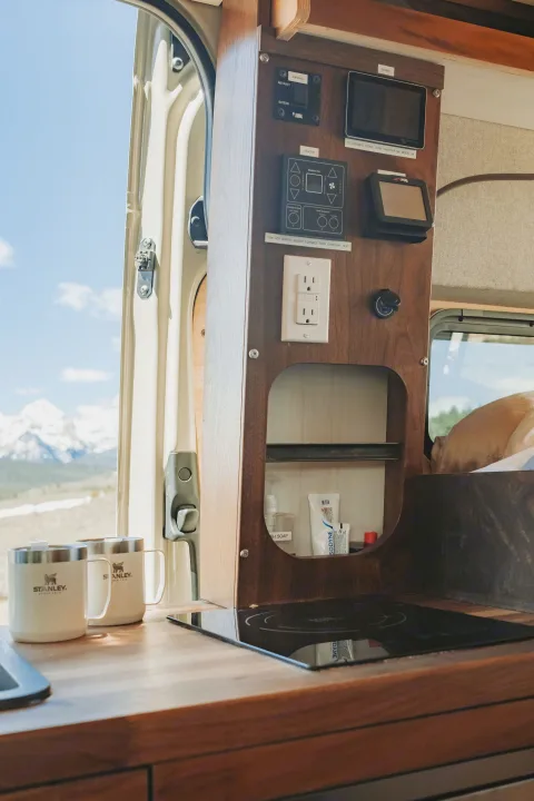 RV rental: Compact kitchen with induction cooktop, control panel, power outlets, and stunning mountain views out the door.. Custom Mercedes Benz Sprinter 2022