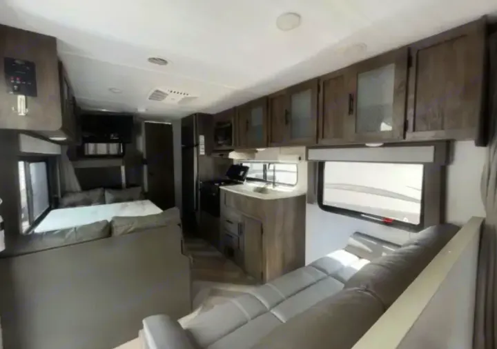 Spacious rv rental interior featuring a modern living area with sofa, kitchen with stove and sink, and convertible dinette.. Forest River Salem Cruise Lite 2020