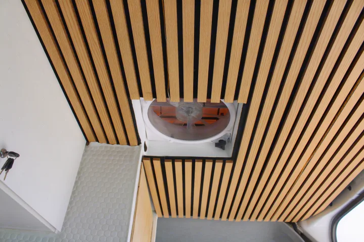 Overhead view of an RV rental interior: slatted wooden ceiling, central vent fan, and white wall with keys.. Mercedes-Benz Sprinter 2008