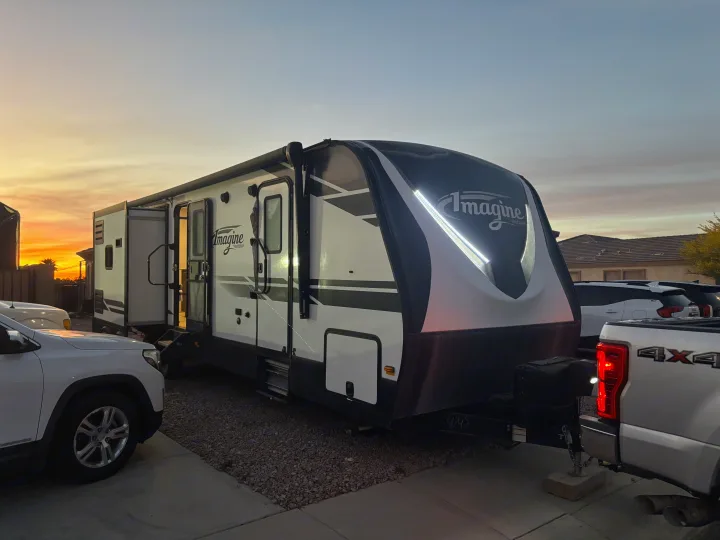 Grand Design Imagine RV rental travel trailer at dusk, bright LED lights on, hitched to a white pickup truck.. Imagine Imagine design 2020