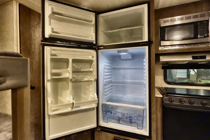 RV rental kitchen: An empty, open refrigerator (freezer & fridge), microwave, and stove ready for your use.. Forest River Salem Cruise Lite 2020