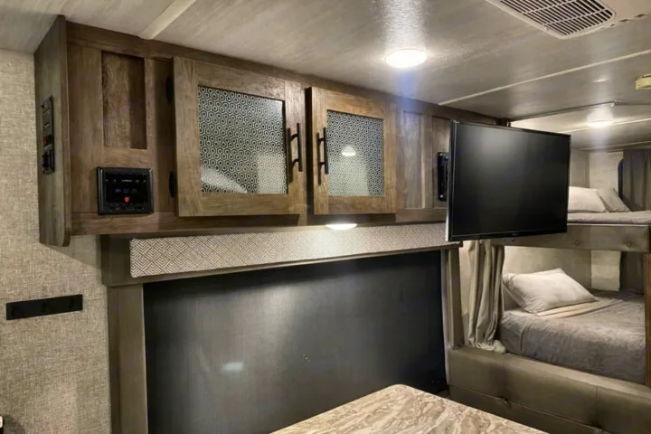 RV rental interior with bunk beds, TV, stereo, and stylish wooden cabinets. Brightly lit.. Forest River Salem Cruise Lite 2020