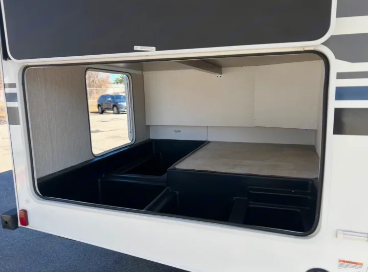Spacious RV rental pass-through storage with black molded bins and raised platform, perfect for organizing gear.. Coachmen Freelander 2021