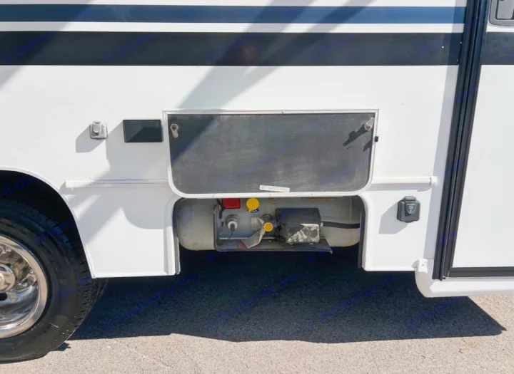 RV rental's side with open utility compartment, revealing the propane tank, hookups, and an exterior power outlet.. Coachmen Freelander 2021