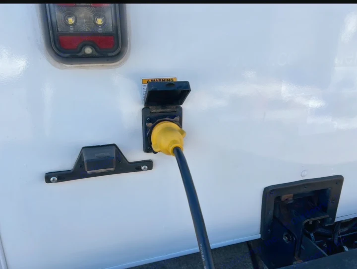 RV rental connected to shore power via yellow cord. Exterior view shows tail light, power inlet. Essential for camping.. Coachmen Freelander 2021