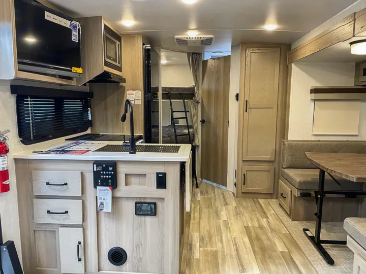 Modern RV rental interior featuring a kitchen, dining area, bunk beds, and wood-look flooring, ready for your next adventure.. Forest River Rockwood Mini Lite 2024