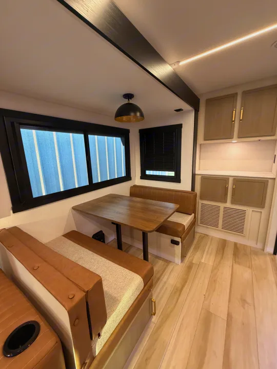 Spacious and modern RV rental interior featuring a dinette with bench seating, sleek black-framed windows, and built-in storage.. Forest River Salem Hemisphere 2026