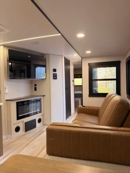 RV rental interior featuring a cozy living room with a brown sofa, mounted TV, and electric fireplace.. Forest River Salem Hemisphere 2026