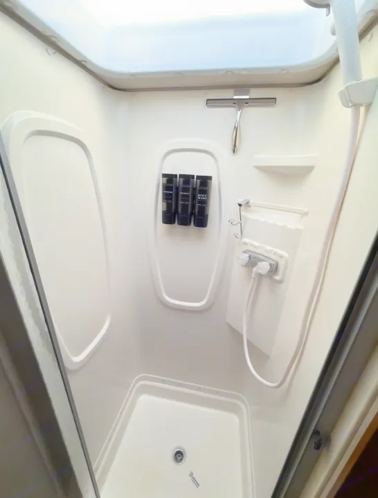Inside an RV rental shower: white molded stall with mounted shampoo, conditioner, body wash, shower head, and a squeegee.. Winnebago Minnie Winnie 2015