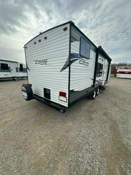 This white Salem Cruise Lite RV rental travel trailer sits on gravel. It has a rear spare tire and awning.. Forest River Salem Cruise Lite 2016