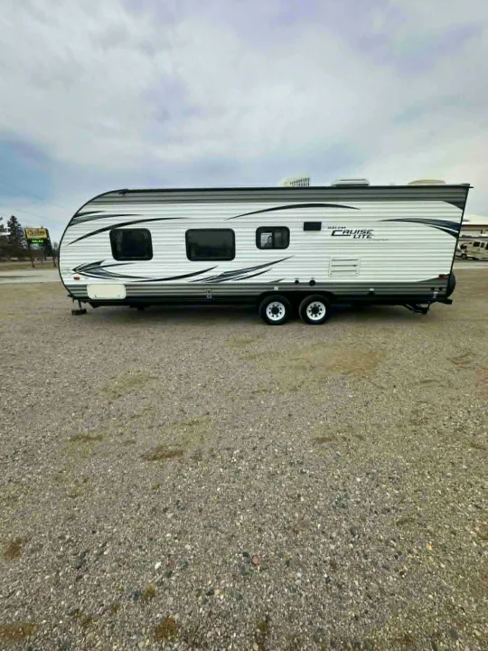 White Cruise Lite travel trailer with black graphics, dual axles, parked on a gravel lot. Great for your next RV rental.. Forest River Salem Cruise Lite 2016
