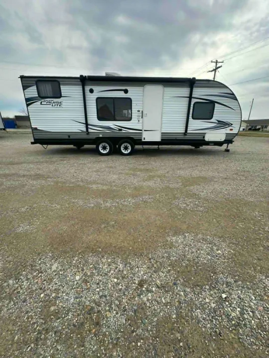White travel trailer on a gravel lot, ready for adventure as an RV rental. Cloudy sky above.. Forest River Salem Cruise Lite 2016