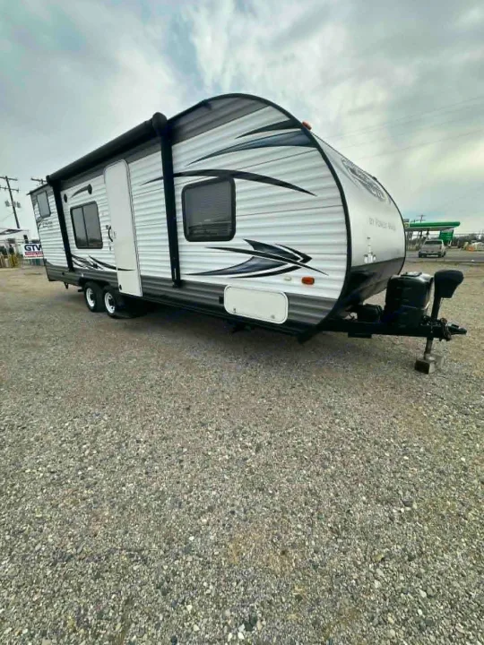 White & gray travel trailer, great for an RV rental or camper getaway. Parked on a gravel lot, awning out.. Forest River Salem Cruise Lite 2016