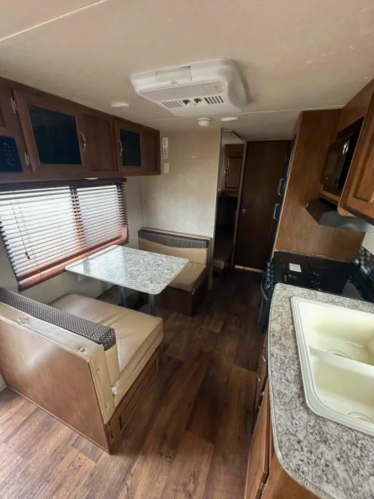 RV rental interior: dinette with window blinds, functional kitchen with double sink, stove, microwave, and ample storage cabinets.. Forest River Salem Cruise Lite 2016